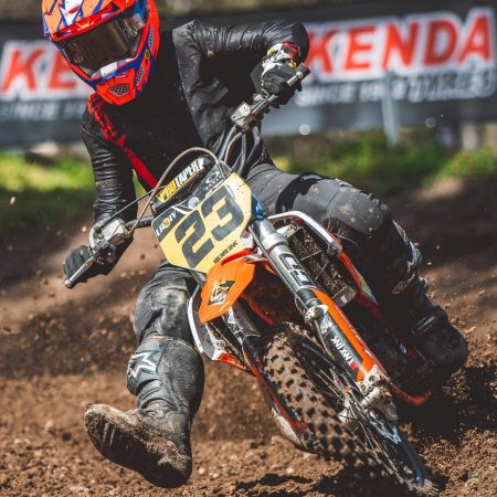 Lachlan Morris tipping it into a right hand corner aboard his ktm 65 wearing the infinite back out pinned black and red motocross gear set